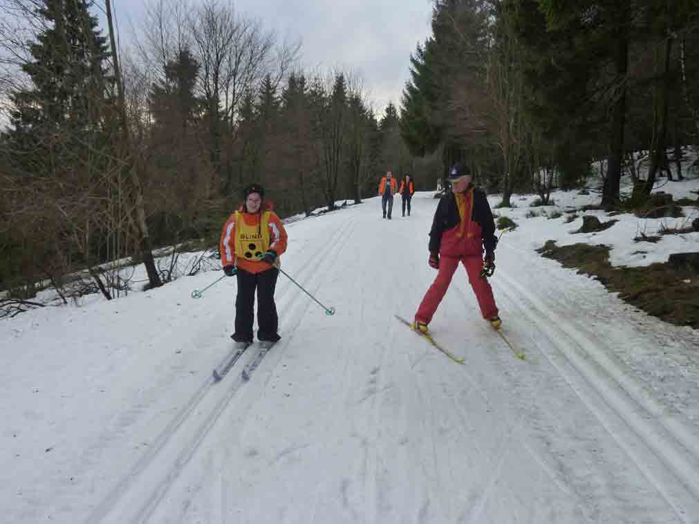 Eine Schülerin wird beim zügigen Fahren mit den Langlaufski von einem Skilehrer begleitet.