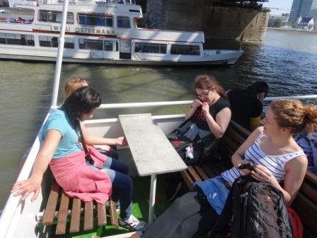 Die Schüler Pariza, Lisa und Isabell sitzen während der Schiffsfahrt mit Frau Kugler an einem Tisch und genießen das schöne Wetter.