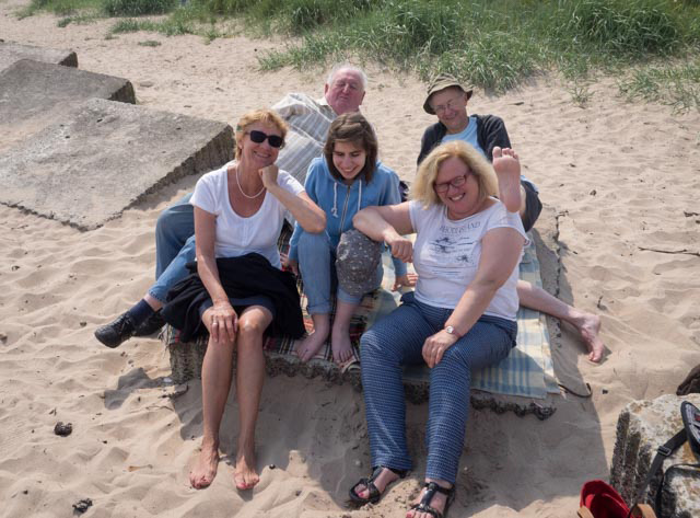 Norman, John, Frau Schlaadt-Großnick, Melissa und Frau Capitain haben es sich auf einer Decke im Sand gemütlich gemacht