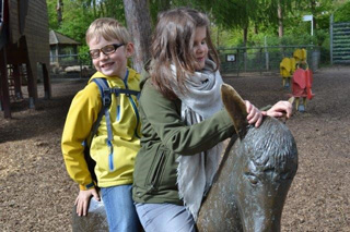 Eva und Anton sitzen auf einem Esel aus Messing.