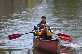 Eva, Anton und Frau Weinhold im Kanu beim Paddeln.