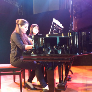 Franziska Staubach und Yizhuo Meng sitzen am Klavier und spielen vierhändig