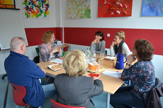 Eltern von GU-Schülerinnen sitzen beim Vortrag von Frau Böttcher im Kurshaus um einen großen Tisch