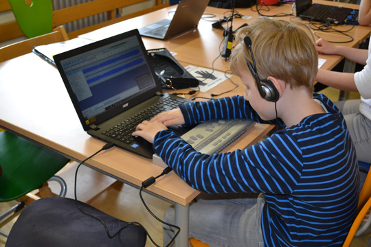 Schüler arbeitet am Laptop mit Braillezeile mit Audacity
