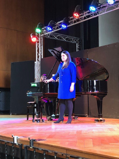 Elena Mohrs steht vor dem Flügel auf der Bühne der LVR-Louis-Braille-Schule