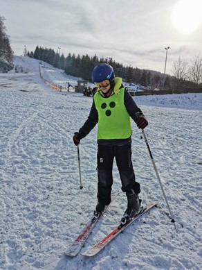 Am Ende eines Skihanges steht ein Schüler auf Skiern.