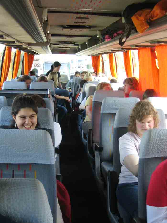 Schüler, Lehrer und Erzieher sitzen im Bus. Im Vordergrund sieht man Sinem, Sarah und Alexandra, die sich auf die Eifel freuen.
