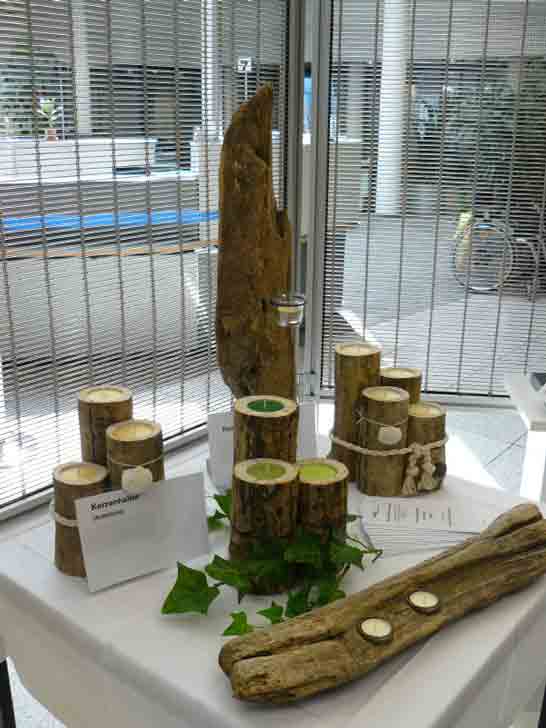 Auf einem Ausstellungstisch stehen verschiedene Kerzenständer aus Treibholz.