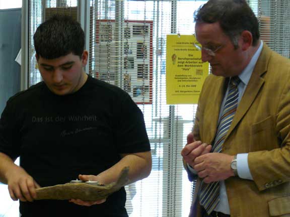 Der Schüler Eren zeigt dem Bürgermeister Herrn Larue einen Holz-Teelichthalter.