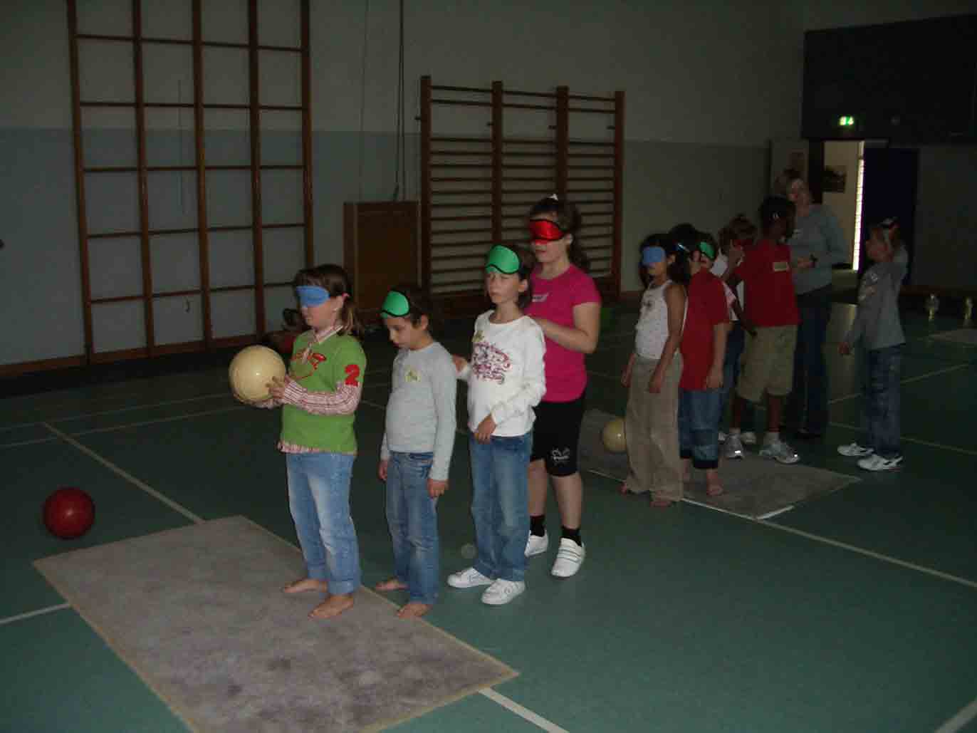 Schüler stehen mit Augenbinde hintereinander in der Turnhalle und warten darauf den Ball zu werfen.
